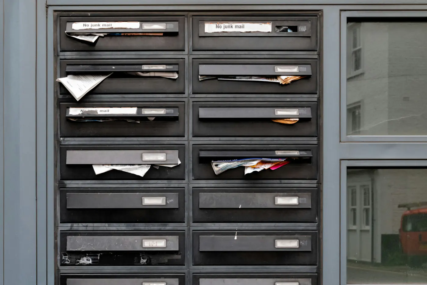Batterie de boîtes aux lettres d'immeuble, du courrier resté coincé dans les fentes de plusieurs d'entre elles
