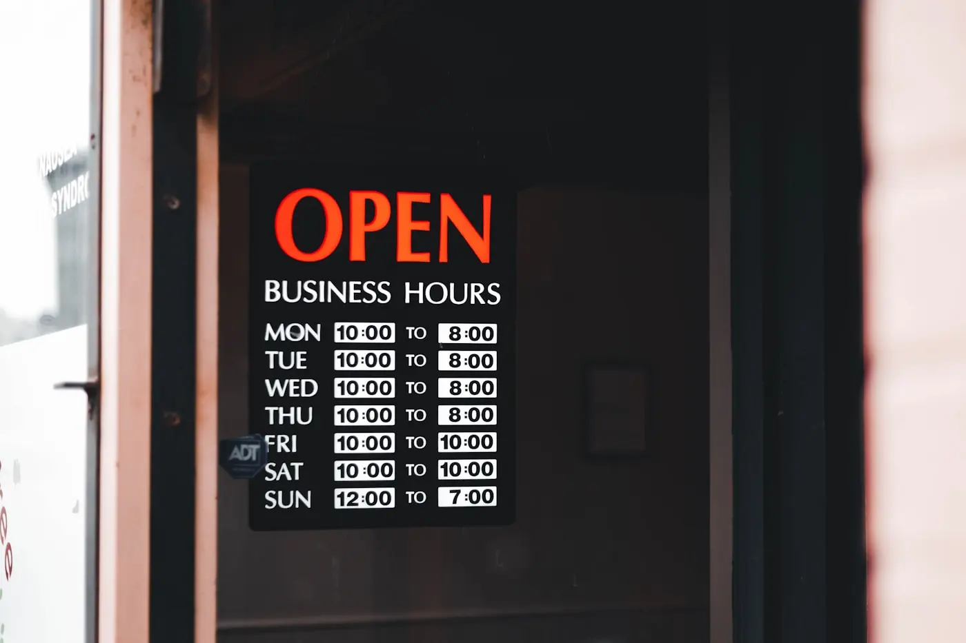 Panneau d'horaires d'ouverture affiché sur la porte vitrée d'un commerce